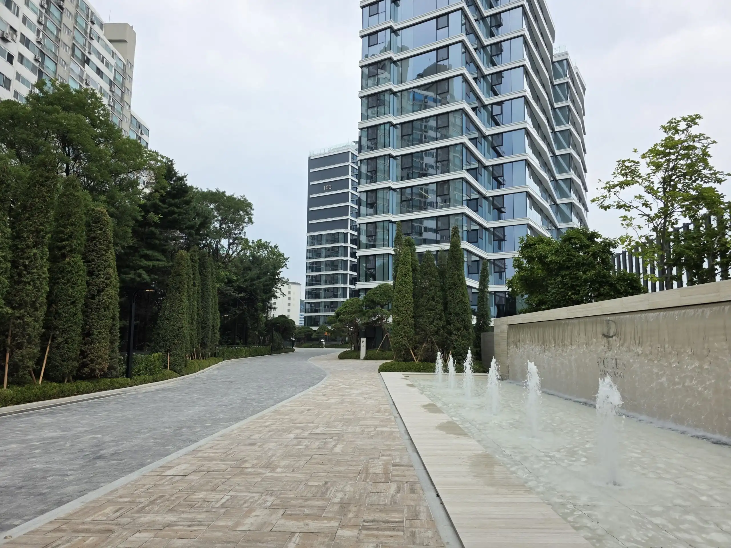 Luxury Seoul apartment building with modern architecture and landscaped gardens.