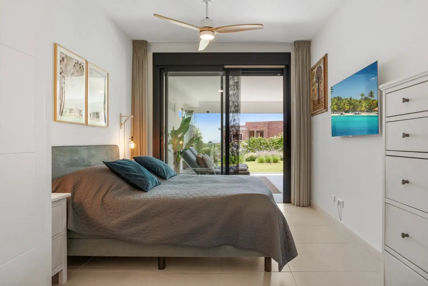 Bright bedroom with large sliding glass doors opening to a garden and outdoor view.