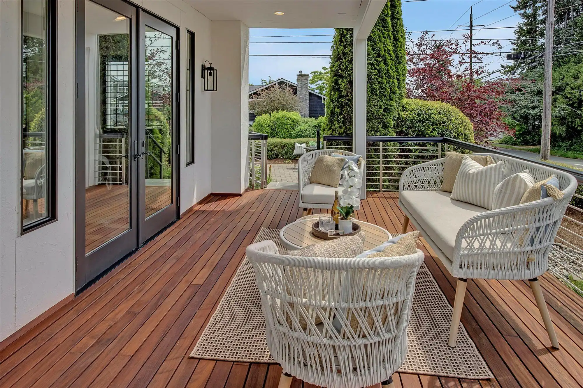 Outdoor porch featuring comfortable wicker furniture and a scenic view of lush greenery and neighbor.
