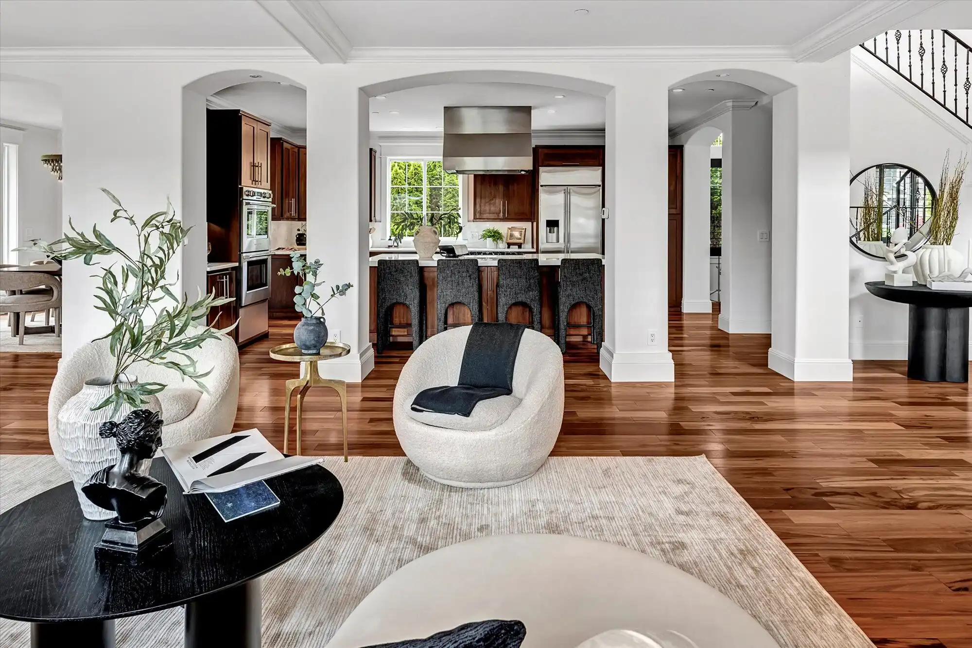 Elegant modern living room with open kitchen and hardwood floors.
