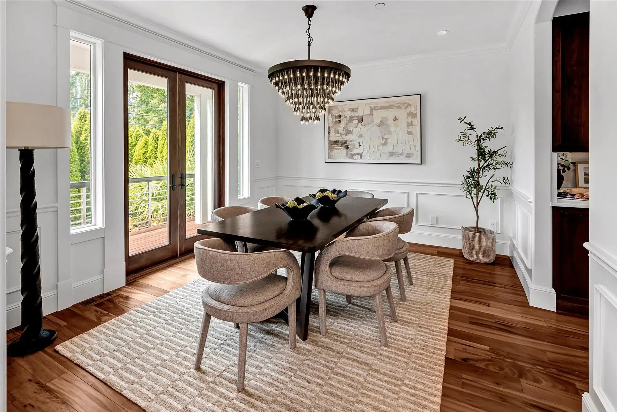 Elegant dining room with large glass doors, chandelier, and stylish decor.