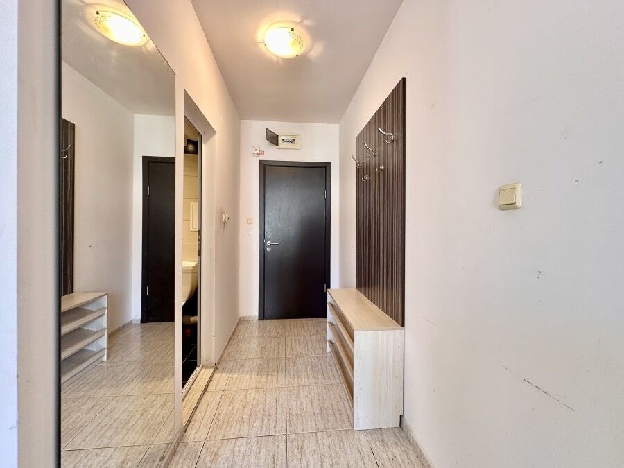 Bright hallway with large mirror and wooden storage units, leading to a modern apartment in Sunny Be.