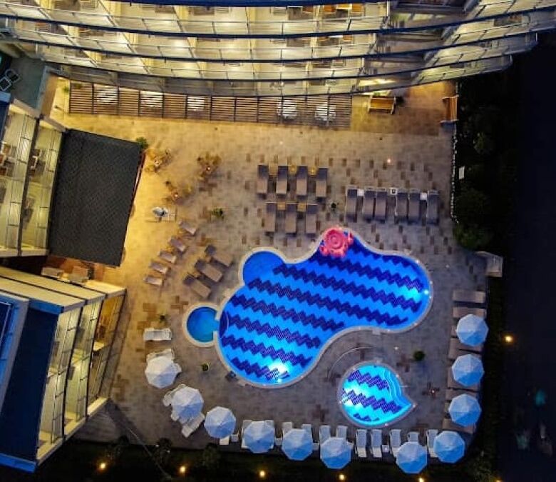 Bright outdoor pool area with sun loungers and umbrellas.