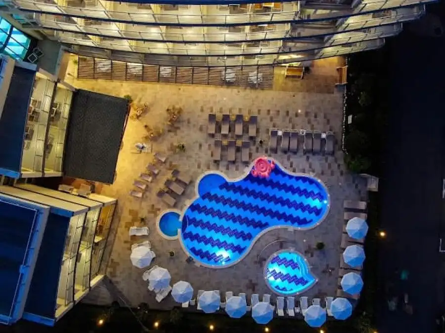 Bright outdoor pool area with sun loungers and umbrellas.