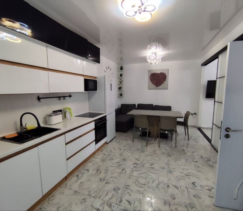 Bright, contemporary kitchen with white cabinets and marble flooring.