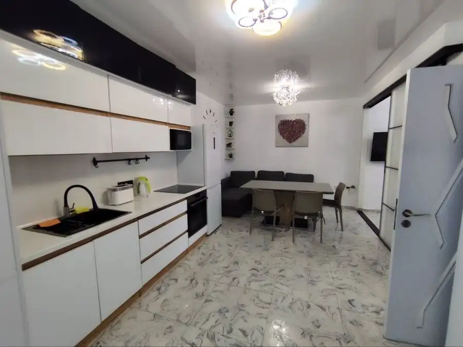 Bright, contemporary kitchen with white cabinets and marble flooring.
