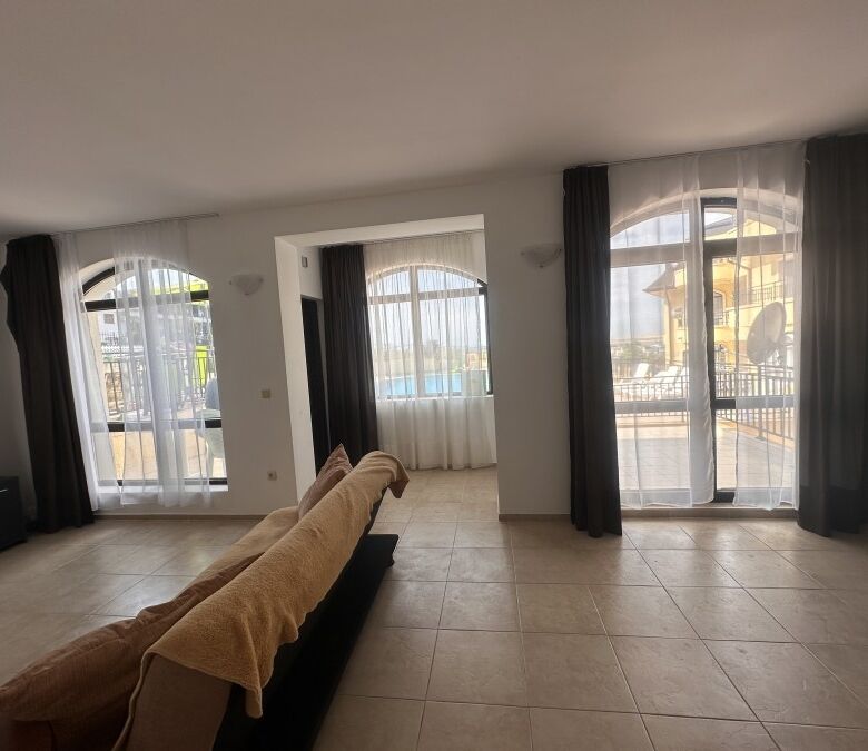 Bright living room with large windows and access to veranda overlooking pool in Nessebar View comple.
