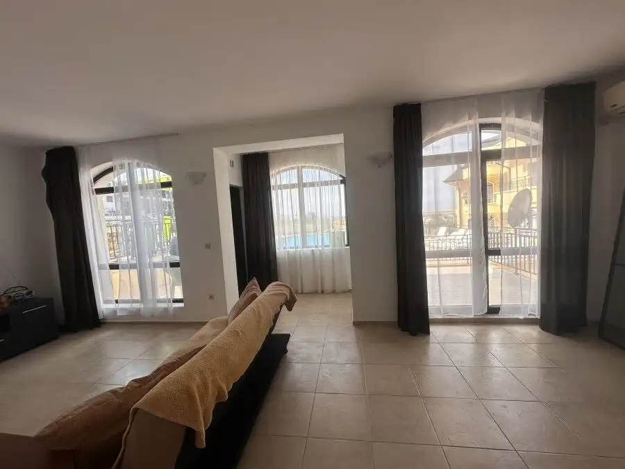 Bright living room with large windows and access to veranda overlooking pool in Nessebar View comple.