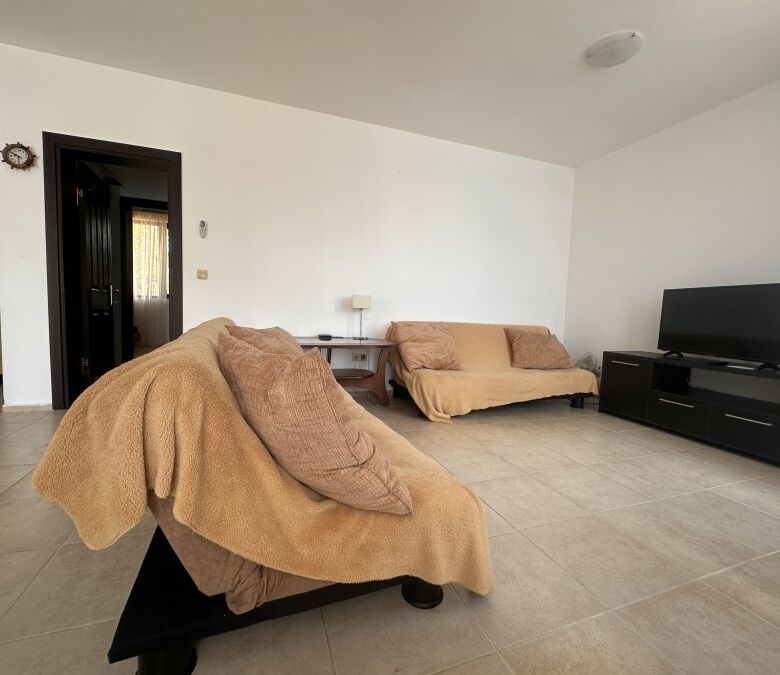 Bright living room with comfortable sofas and modern TV setup in a sunny apartment.