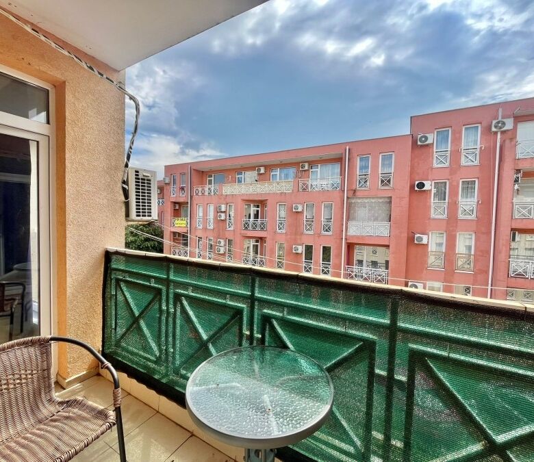 Bright balcony view of a residential complex with pink buildings, air conditioning units, and a clea.