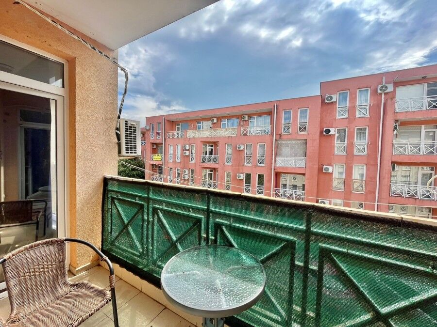 Modern 2-Bed Furnished Apartment Near the Sea Bright balcony view of a residential complex with pink buildings, air conditioning units, and a clea.