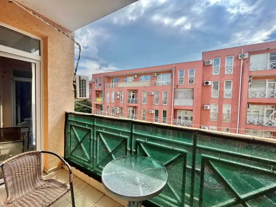 Bright balcony view of a residential complex with pink buildings, air conditioning units, and a clea.