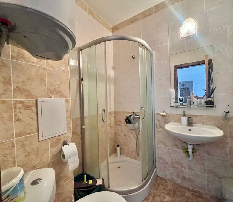 Bathroom with shower enclosure, sink, and toilet in a fully furnished apartment.