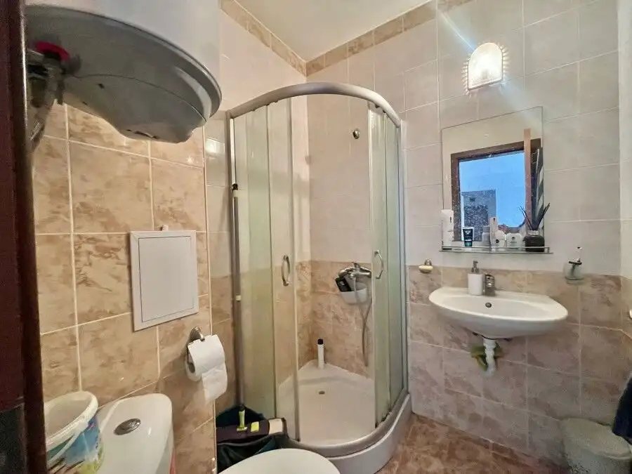 Bathroom with shower enclosure, sink, and toilet in a fully furnished apartment.