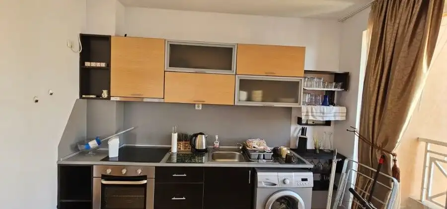 Bright kitchen featuring appliances, cabinets, and a window with curtains.