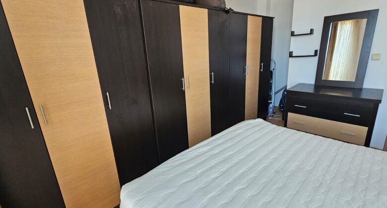 Bedroom with large wardrobe, dresser, and window in a sunny apartment.