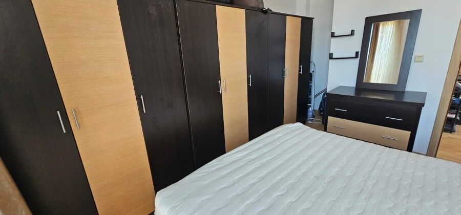 Modern bedroom with built-in wardrobe and dresser Bedroom with large wardrobe, dresser, and window in a sunny apartment.