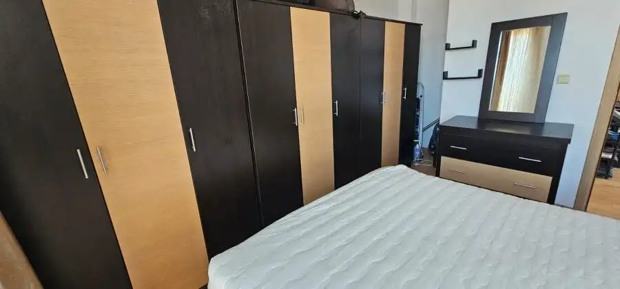 Bedroom with large wardrobe, dresser, and window in a sunny apartment.