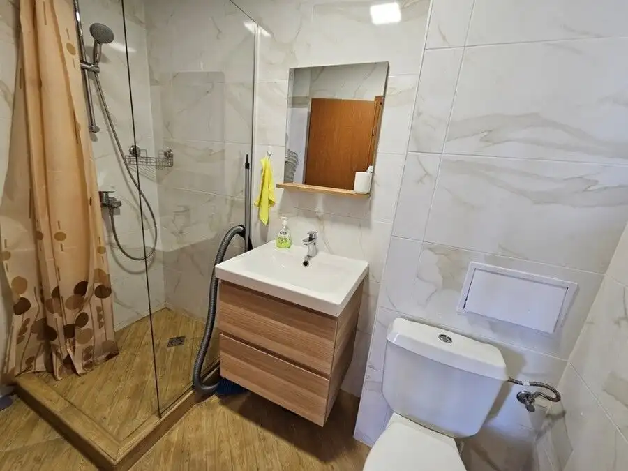 Bright bathroom with shower, sink, and toilet in a compact studio apartment.