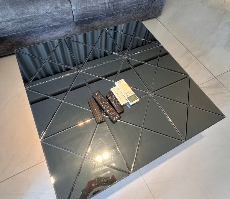 Modern black mirrored coffee table with geometric design in a stylish living room.