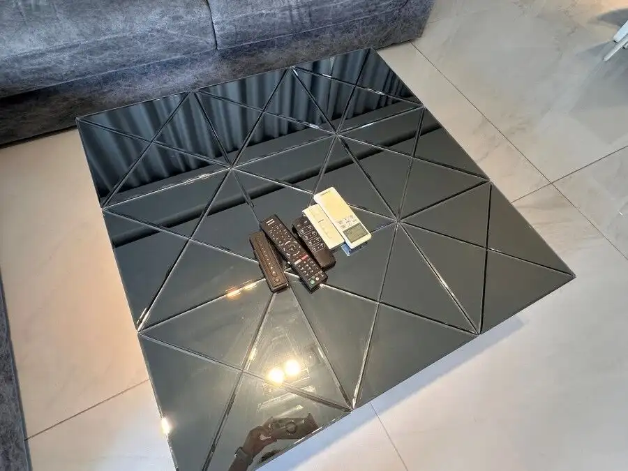 Modern black mirrored coffee table with geometric design in a stylish living room.