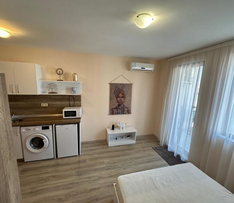 Interior view of a studio apartment with kitchen, washing machine, and living area in Apollon Ravda.