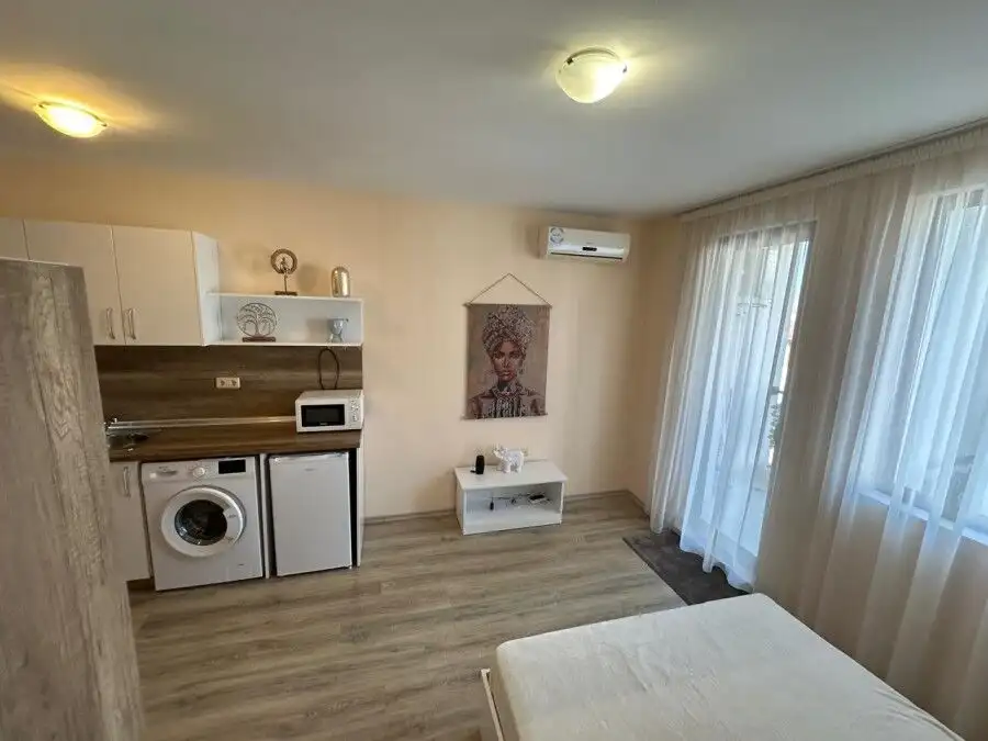 Interior view of a studio apartment with kitchen, washing machine, and living area in Apollon Ravda.