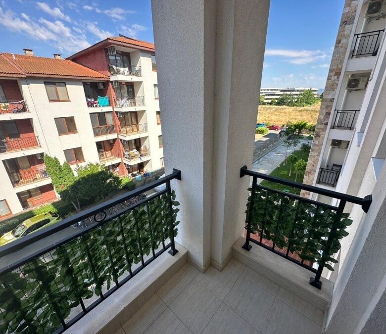 Balcony view from Apollon apartments in Ravda, overlooking neighboring buildings and greenery.