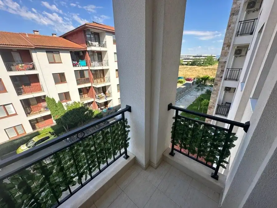 Balcony view from Apollon apartments in Ravda, overlooking neighboring buildings and greenery.