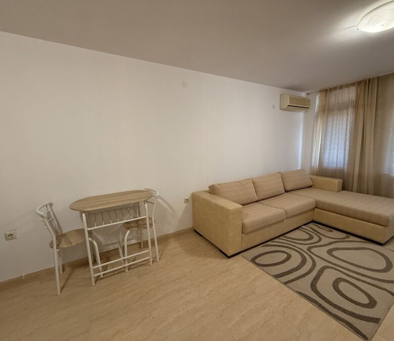 Interior of a spacious studio apartment in Etara 3, St. Vlas, near the sea, with a large beige sofa.
