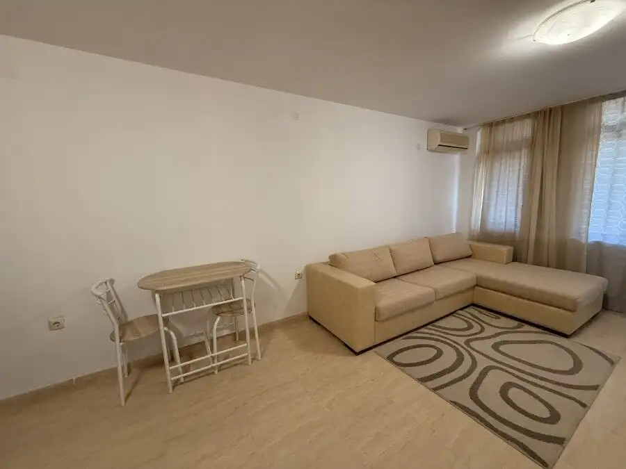 Interior of a spacious studio apartment in Etara 3, St. Vlas, near the sea, with a large beige sofa.