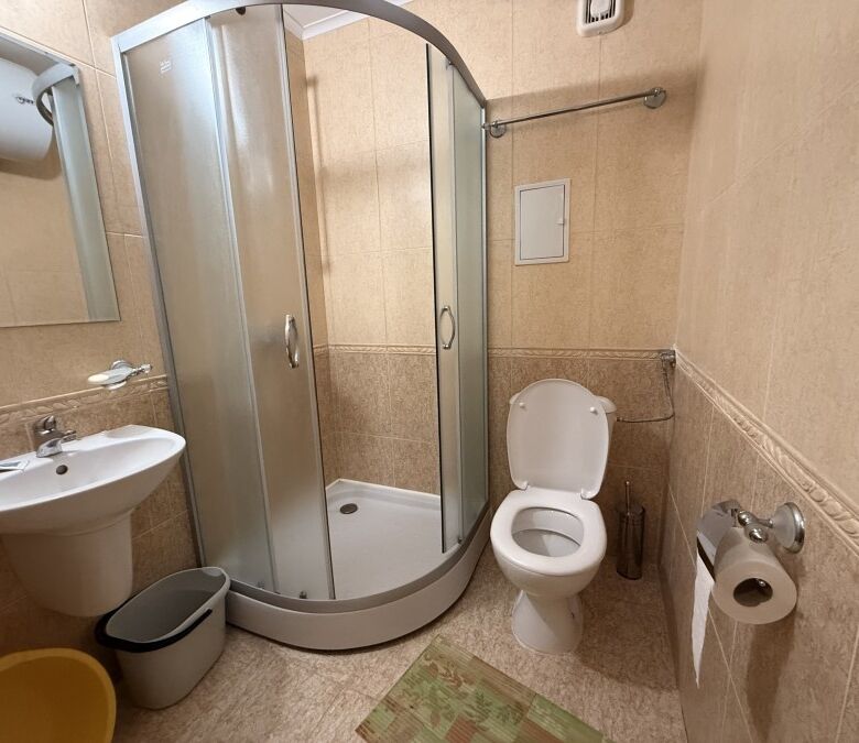 Bright bathroom with shower, toilet, and sink in a 38 sq.m. studio apartment near the sea.