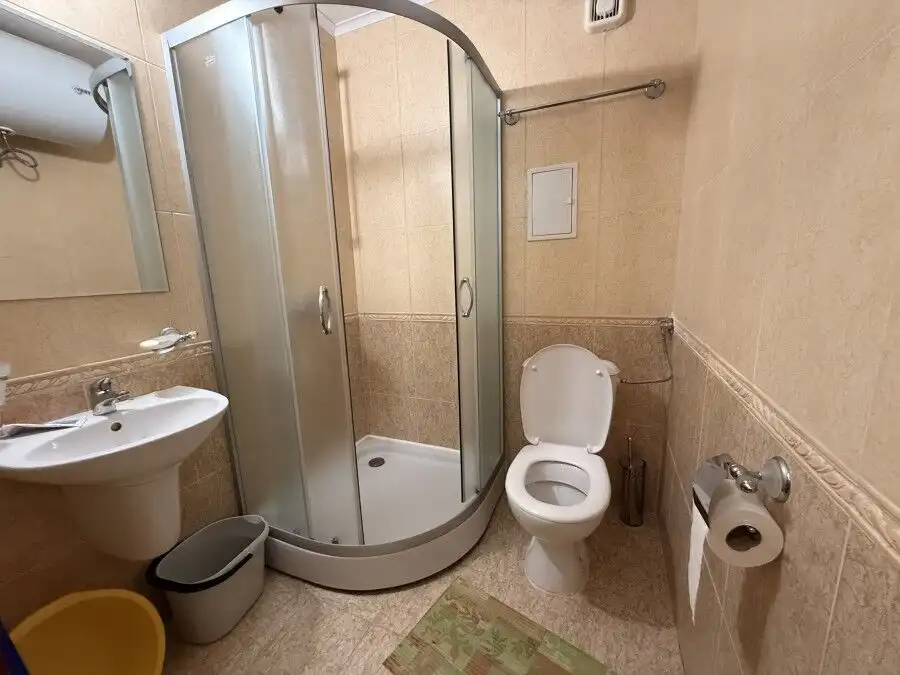 Bright bathroom with shower, toilet, and sink in a 38 sq.m. studio apartment near the sea.