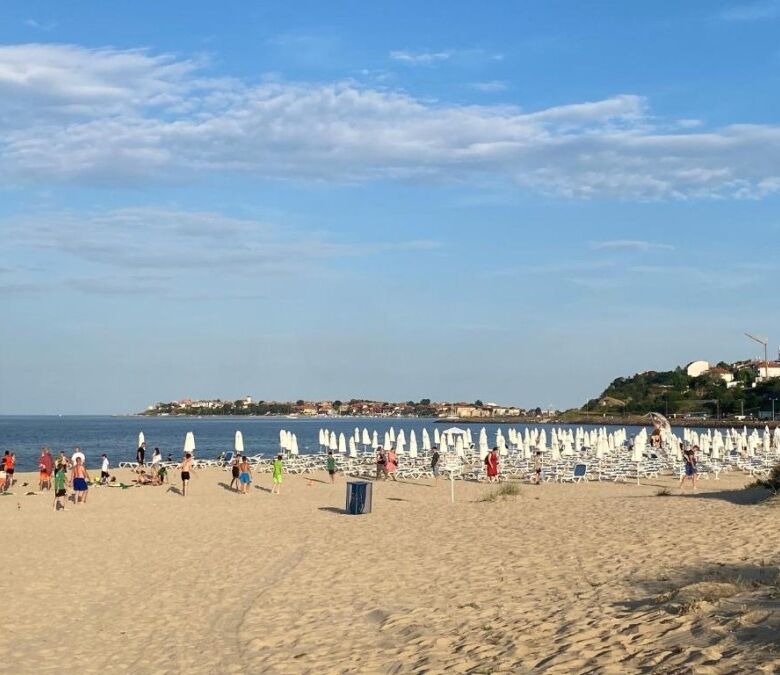 Beach view of Esperanto hotel with sunbeds and umbrellas on the seaside.