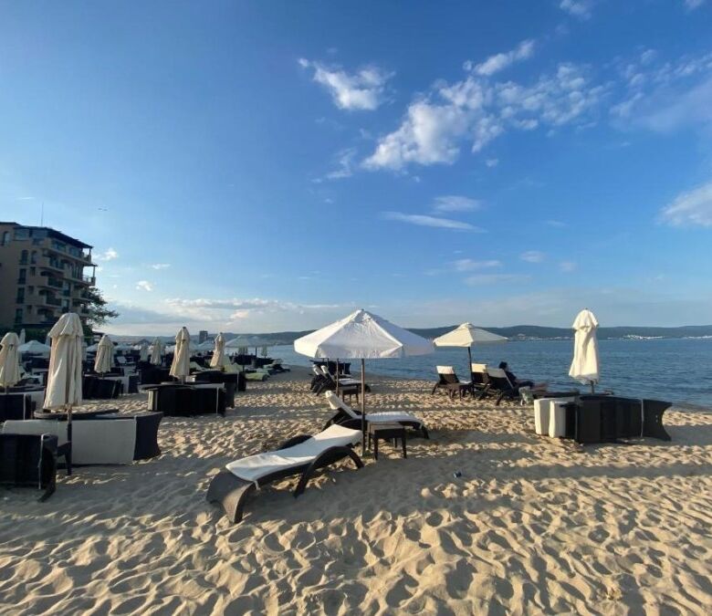 Beachfront hotel Esperanto with sun loungers and umbrellas on sandy shore.