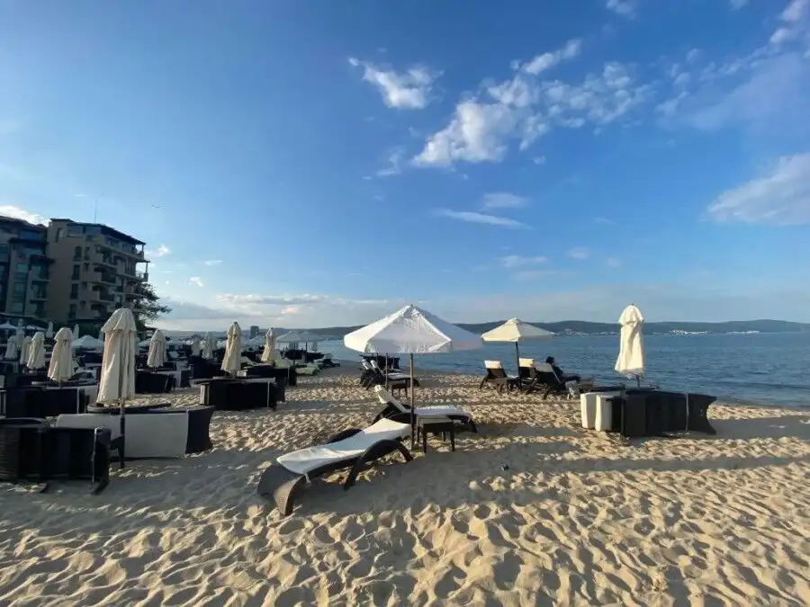 Beachfront hotel Esperanto with sun loungers and umbrellas on sandy shore.