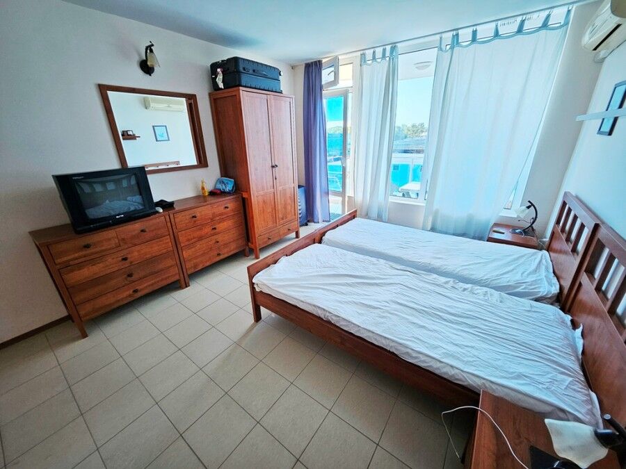 Sea view hotel room with twin beds, wardrobe, and TV.