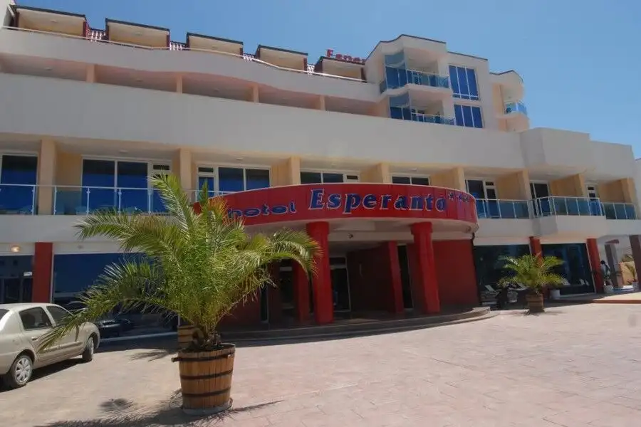 Esperanto hotel front view with palm trees and parking area.