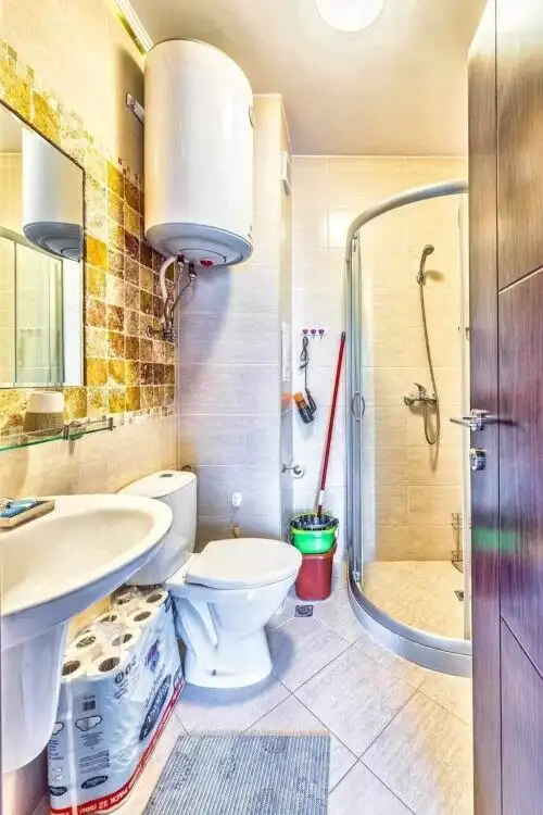 Bright bathroom with shower, toilet, and water heater in a compact space.