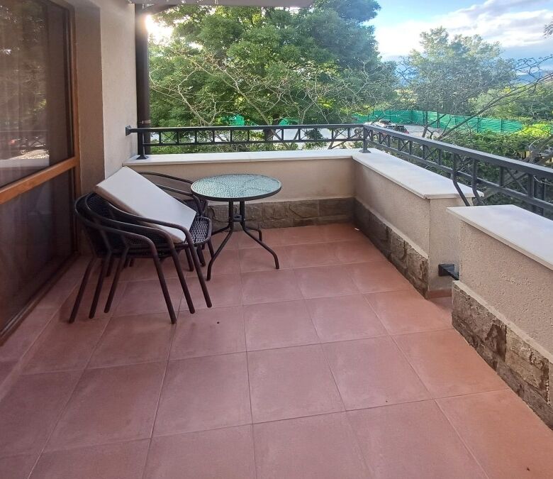 Balcony with pool view, outdoor seating, and lush greenery in Cascadas Family Resort, Sunny Beach.