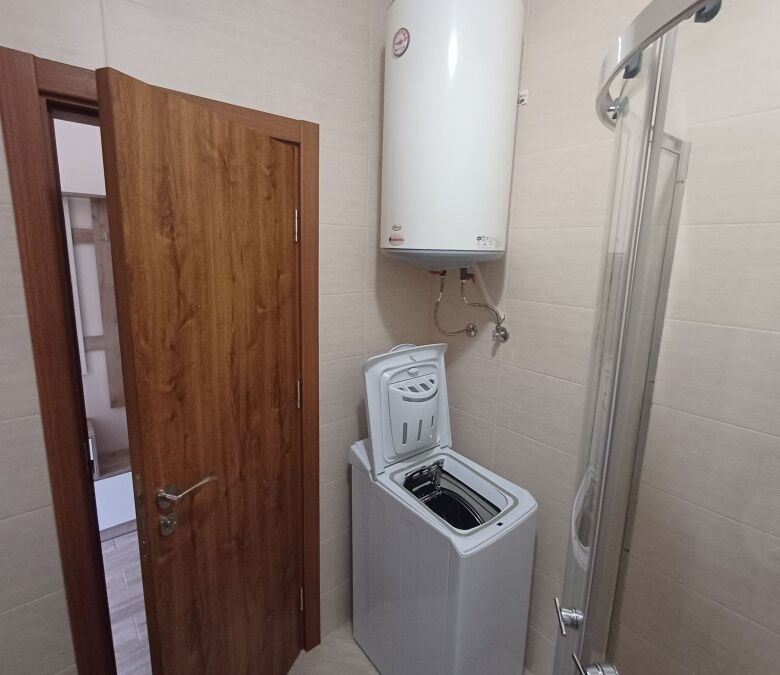 Compact bathroom with washing machine and water heater in Cascadas Family Resort.