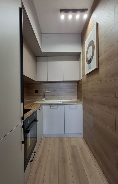 Modern kitchen with white cabinets and wooden accents in a luxury apartment.