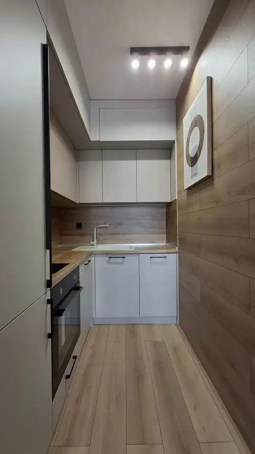 Modern kitchen with white cabinets and wooden accents in a luxury apartment.