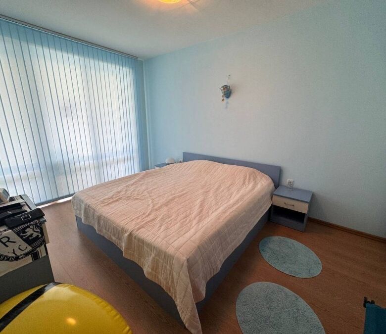 Bright bedroom with large window overlooking pool area in Sunny Beach apartment.