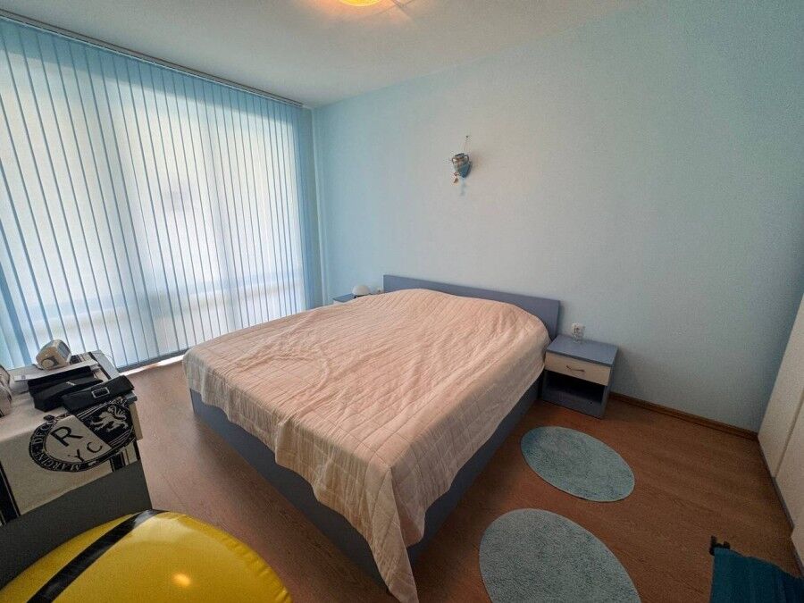 Bright bedroom with large window overlooking pool area in Sunny Beach apartment.
