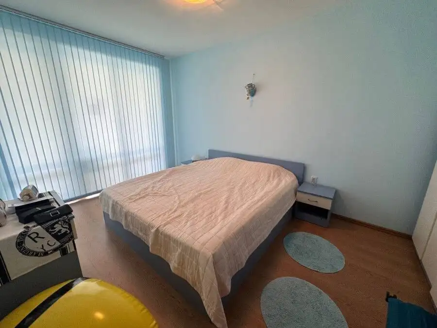 Bright bedroom with large window overlooking pool area in Sunny Beach apartment.
