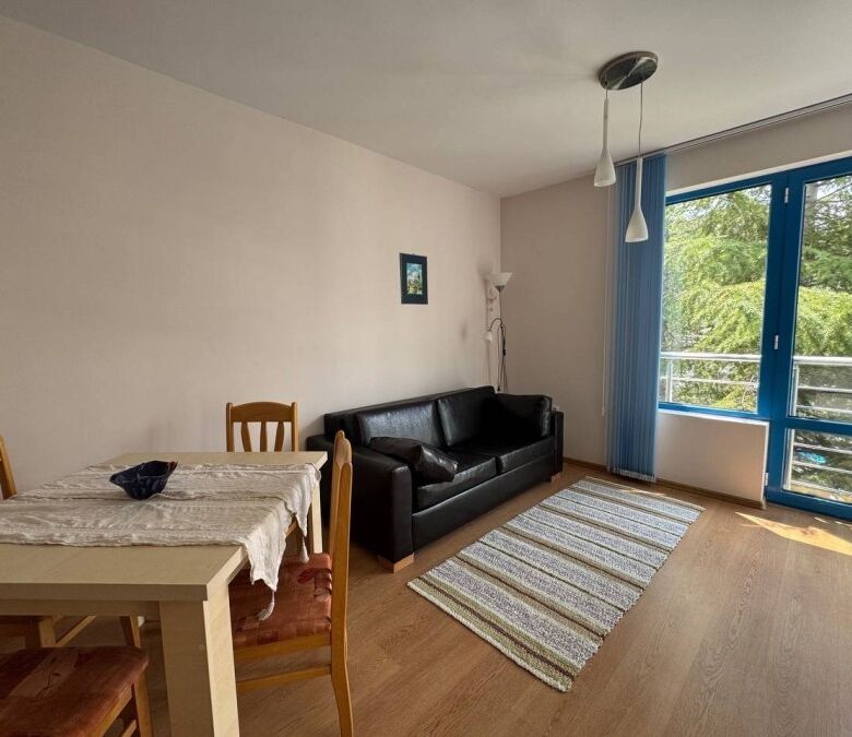 Interior of a 1-bedroom apartment with pool view, sunny beach, and balcony.