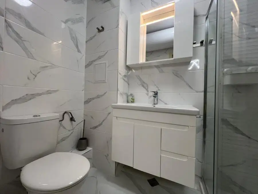 Bathroom with white marble tiles, modern sink, and mirror in top-class complex Valencia Gardens, Nes.