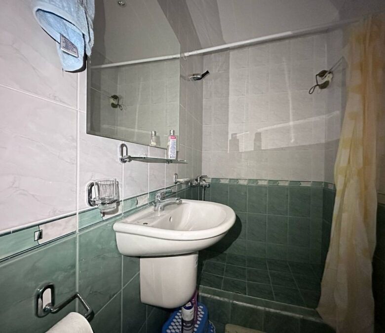 Small bathroom with sink, mirror, and shower in a sea-front apartment in Coral Beach, St. Vlas.