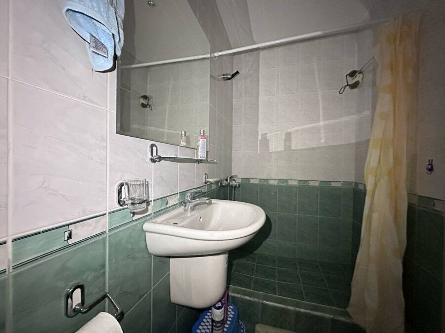 Small bathroom with sink, mirror, and shower in a sea-front apartment in Coral Beach, St. Vlas.